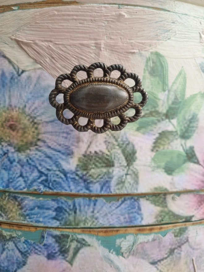 A painted dressing table in white and pale pink with large florals in blues and mauves and text in turquoise that reads 'turn your face to the sun'. The whole piece is distressed in the shabby chic style.