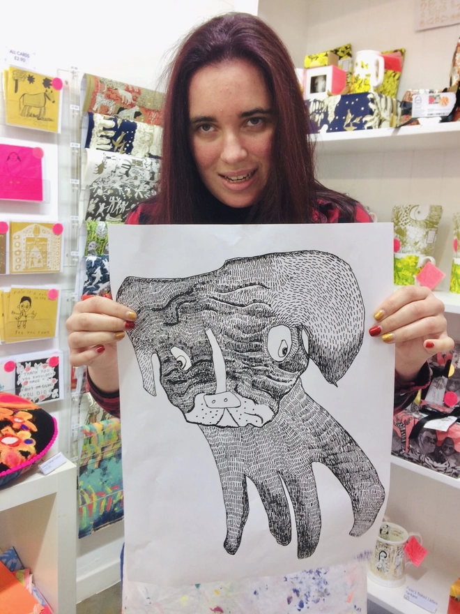 Smiling artist holding a pencil drawing of a cute dog for charity chocolate packaging