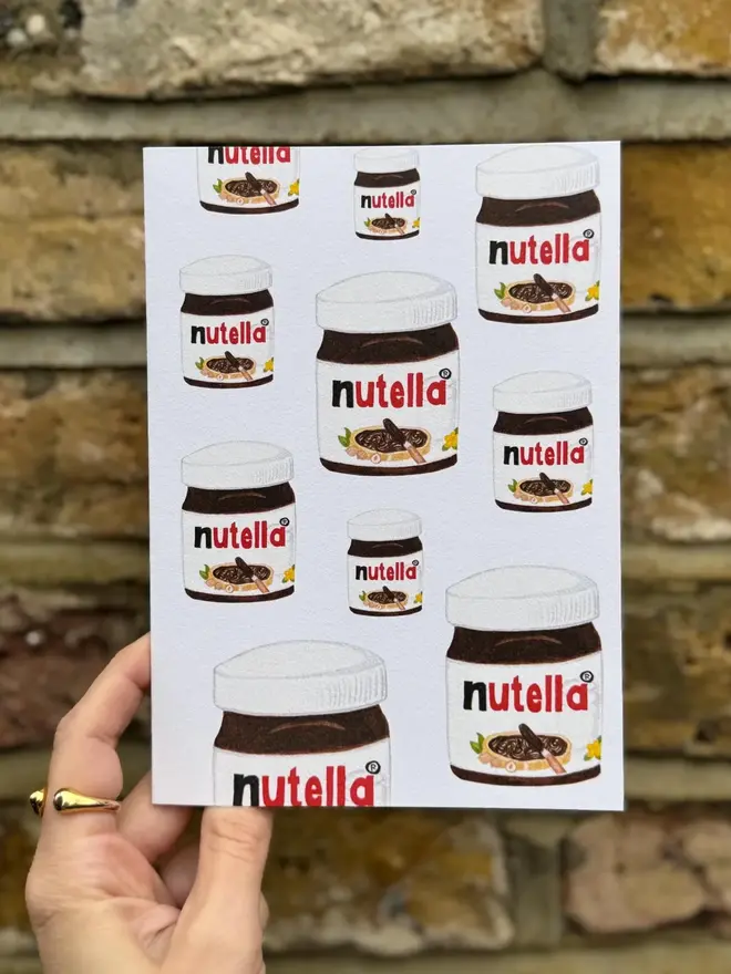 nutella jars illustrated card. card photographed against brick wall backdrop.
