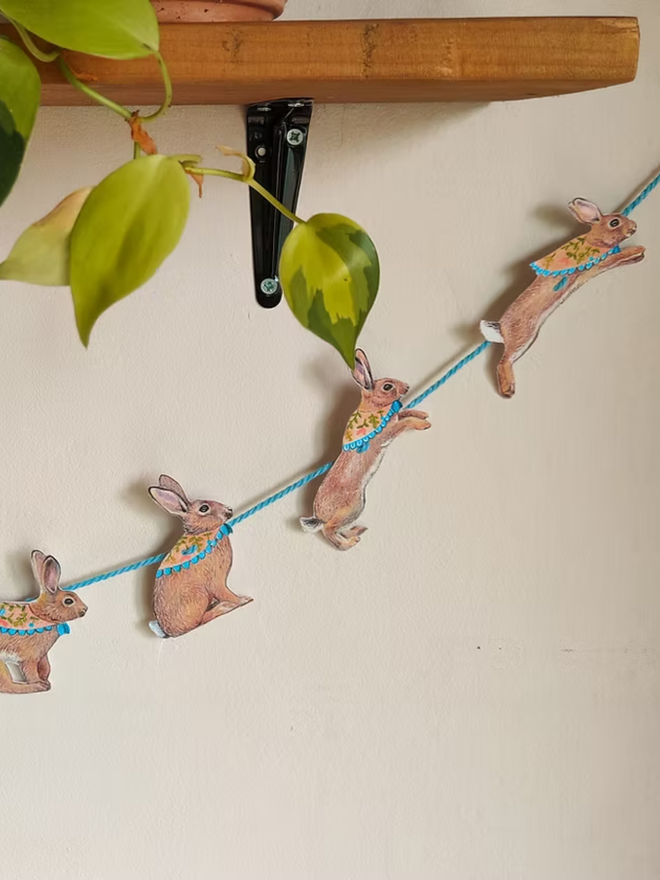 illustrated easter bunny garland. bunnies with easter scarves on bunting hung on a wall.