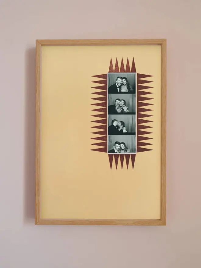 The chevron photobooth mount  frame with a yellow mount featuring a decorative chevron border around a centered Instax photo, displayed on a neutral beige wall.