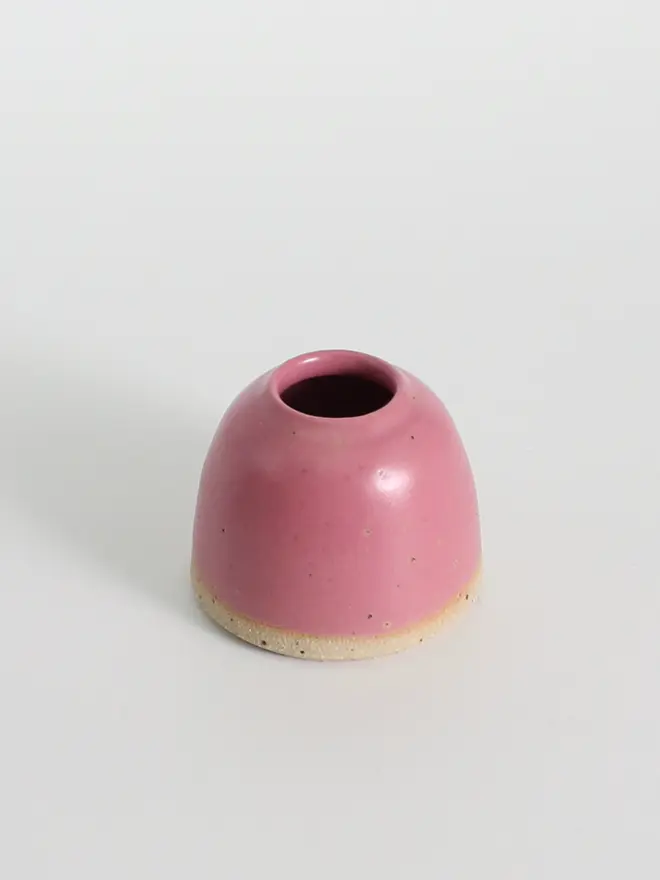 Mini fuchsia ceramic vase against a white background.
