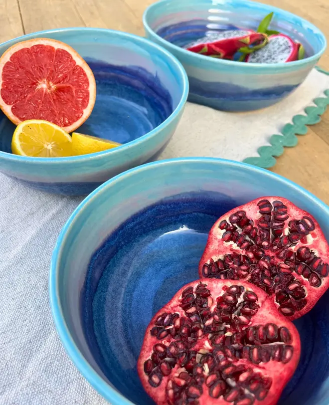 Landscape Serving Bowls (Set Of 3), a collection of colourful serving bowls on a table. They are accompanied by some fruits. 