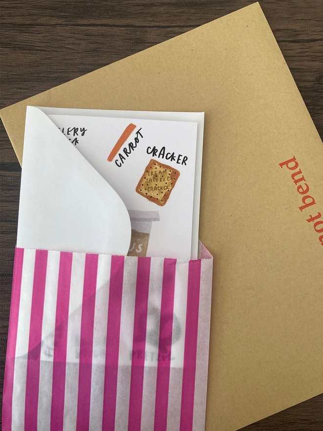 Houmous card packed with a white envelope inside a paper bag