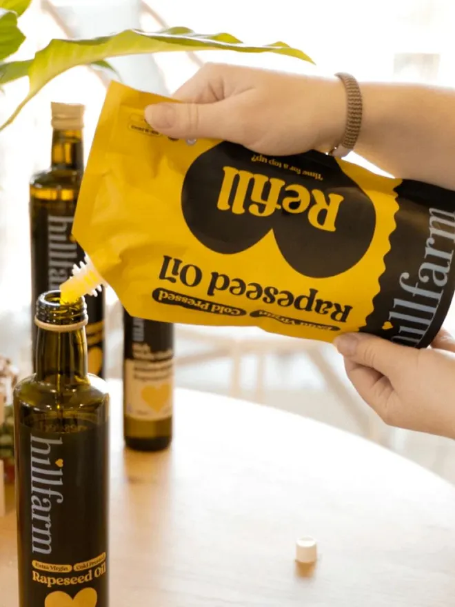 yellow pouch of rapeseed oil being poured into glass bottle