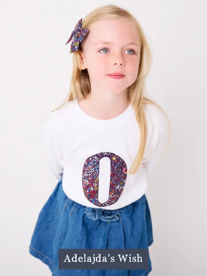 a 5 year old girl wearing a personalised kids white t-shirt with an initial cut from liberty wish starl print on the front
