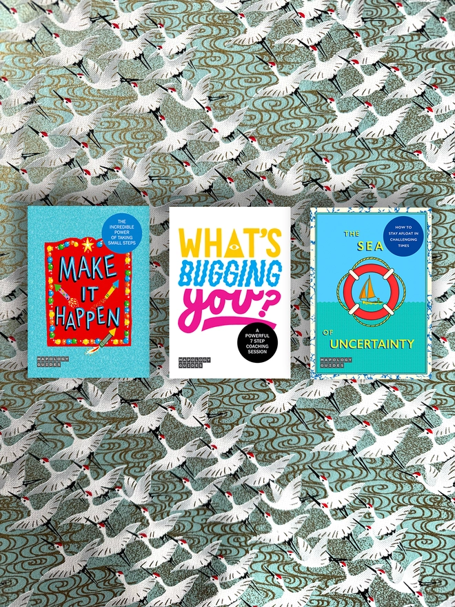 A bundle of three front Mapology Guides covers on a multi-coloured and multi-patterned background. The maps are: Mapology Guide Make It Happen cover – colourful design with rockets and bold typography. Illustrated cover of Mapology Guide titled “What's Bugging You? - a powerful 7 step coaching session” with hand-drawn, vibrant, coloured typography. Illustrated cover of Mapology Guide titled “How To Grow Your No” with lush greenery and flowers.