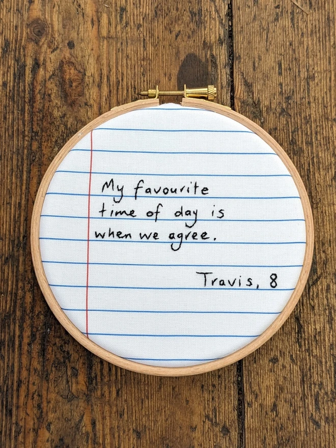 An embroidery hoop with fabric that looks like lined paper The stitching reads "my favourite time of day is when we agree".