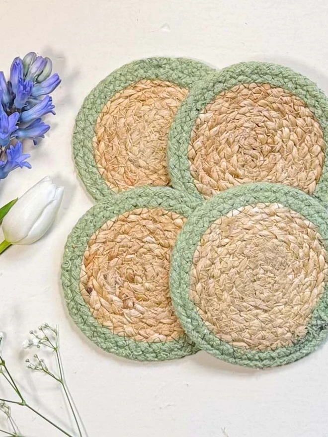 Seagrass coaster with olive rings, shown on a light surface with purple flowers. 