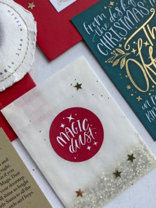 A glassine Magic Dust packet with a red sticker and gold stars beside the green certificate.