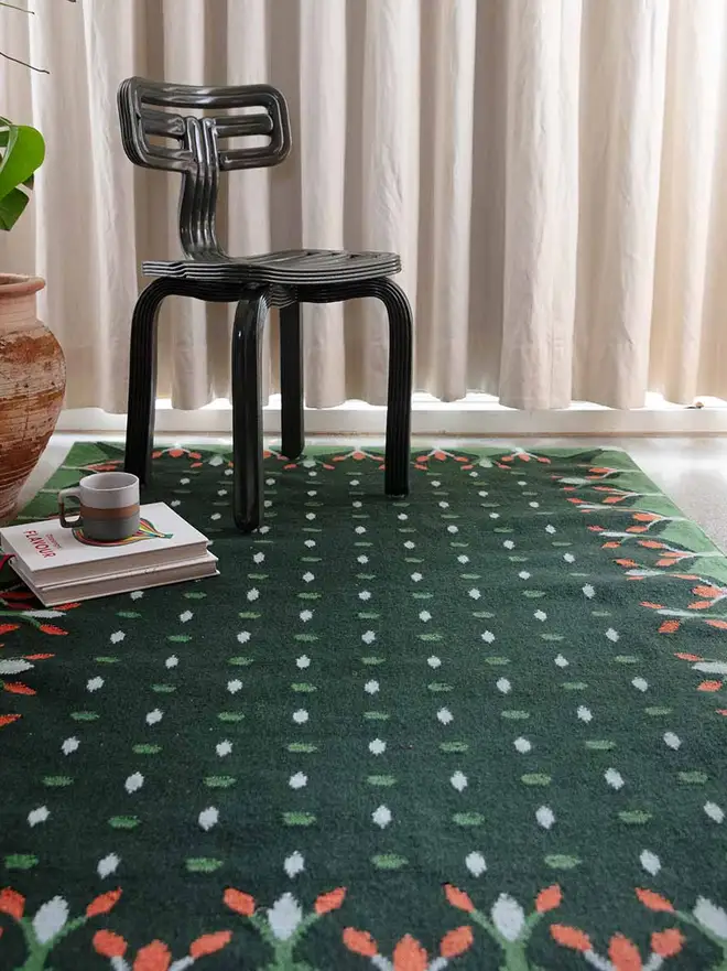 Hedgerow Flatweave Rug, a colourful rug sitting in a decorated room. It is accompanied by some household items. 