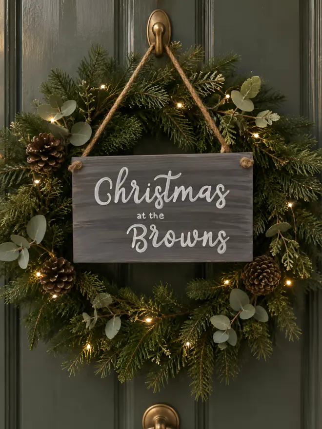 a front door with a christmas wreath and a personalised christmas sign saying 'Christmas at the Brown's'