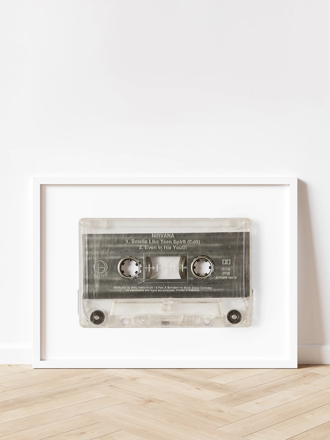 Nirvana 'Smells Like Teen Spirit cassette tape print. framed print propped up against white wall and wooden floor.