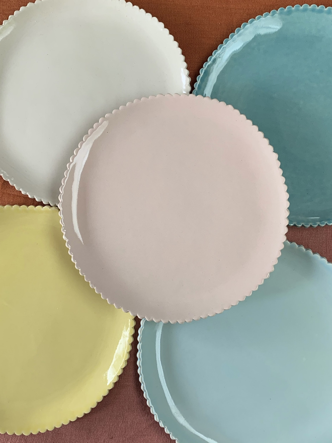 five scalloped edge plates in pastel colours