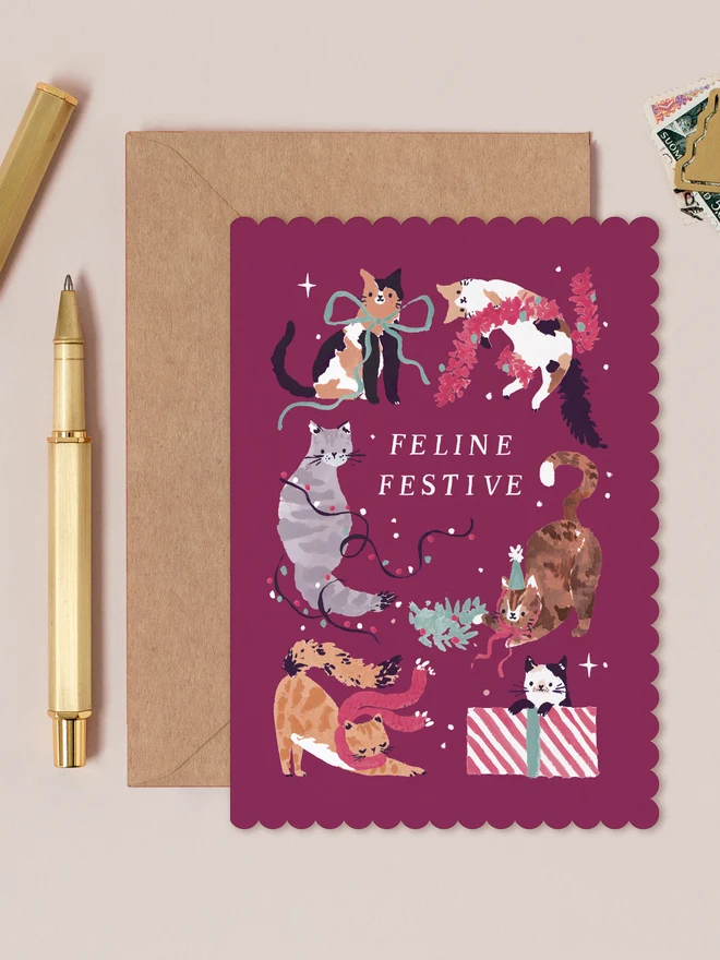 Feline Festive Cats Christmas Card by Sister Paper Co, six cats playing with lights, decorations and gifts on a mulled wine background with a scalloped edge