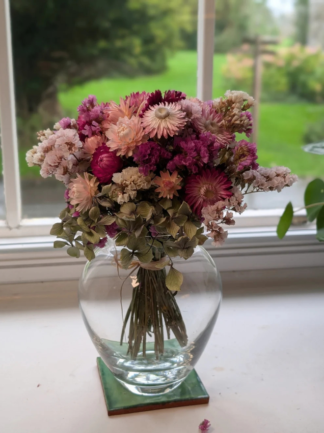 pink petals dried flower bouquet. bouquet of pink dried flowers in a round glass vase.