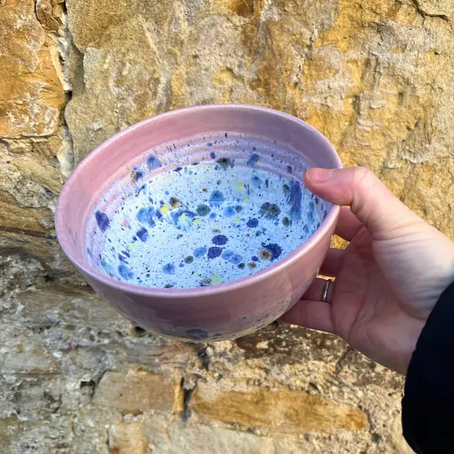 Shoreline Ramen Bowl, a person holding a colourful ramen bowl against a brick backdrop. 