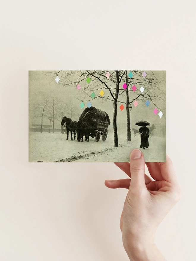 A victorian winter street scene depicting a woman holding an umbrella and a horse and carriage. Trees are draped with fairy lights.