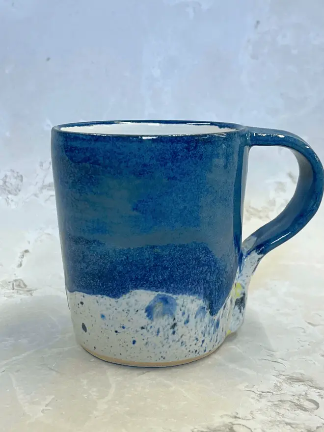 Shoreline Standard Mug, a colourful mug placed on a stone surface. 