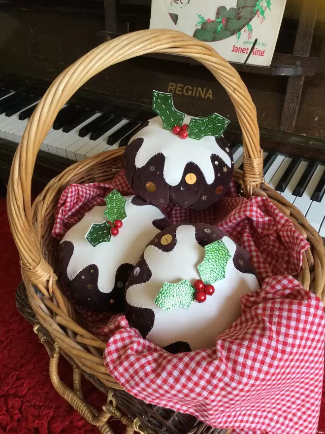 A wicker basket filled with three velvet Christmas pudding table decorations