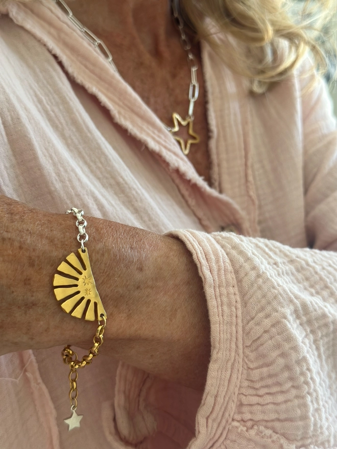 model wears a gold plate sun charm on mixed metal belcher chain bracelet with a mini star in silver