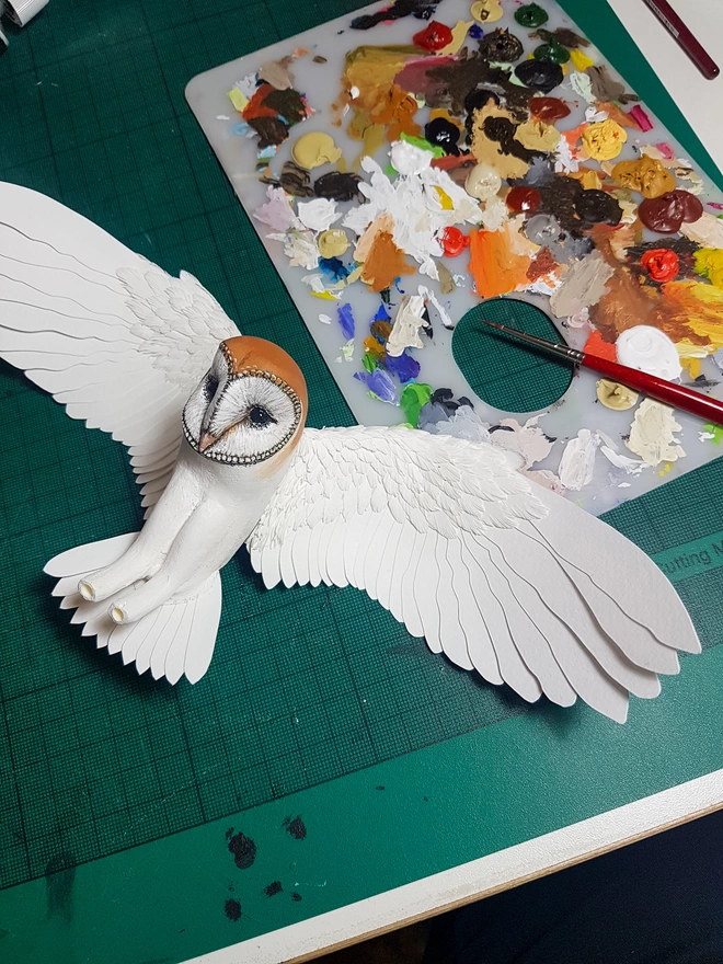 Handmade paper barn owl sculpture being painted in studio