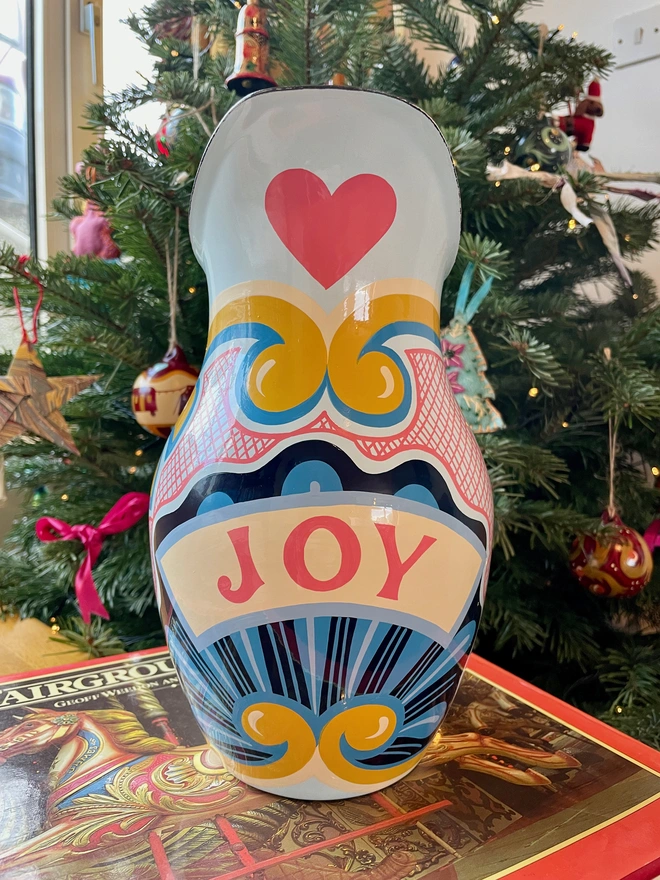 Blue enamel jug hand painted with a fairground design in blue, pink and yellow. 'Joy' is painted in a banner across the centre. 