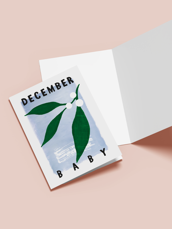 december baby illustrated card. a blue card with mistletoe in the centre.