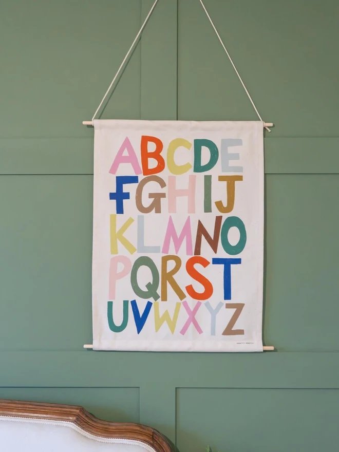 Rainbow Alphabet Fabric Banner, hanging on a green wall. 