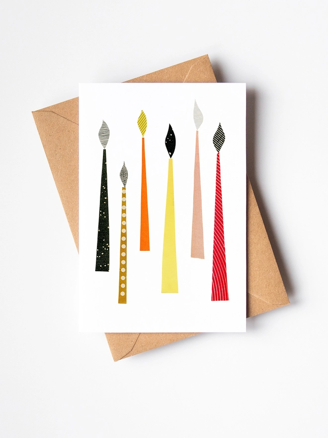 A Christmas card featuring mid century style festive candles in rich colours.