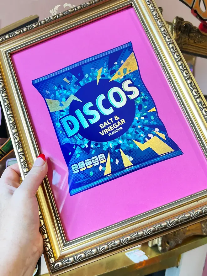 'Disco Salt & Vinegar Flavour' ScreenPrint, a colourful discos print sitting in a gold frame held by a person. 
