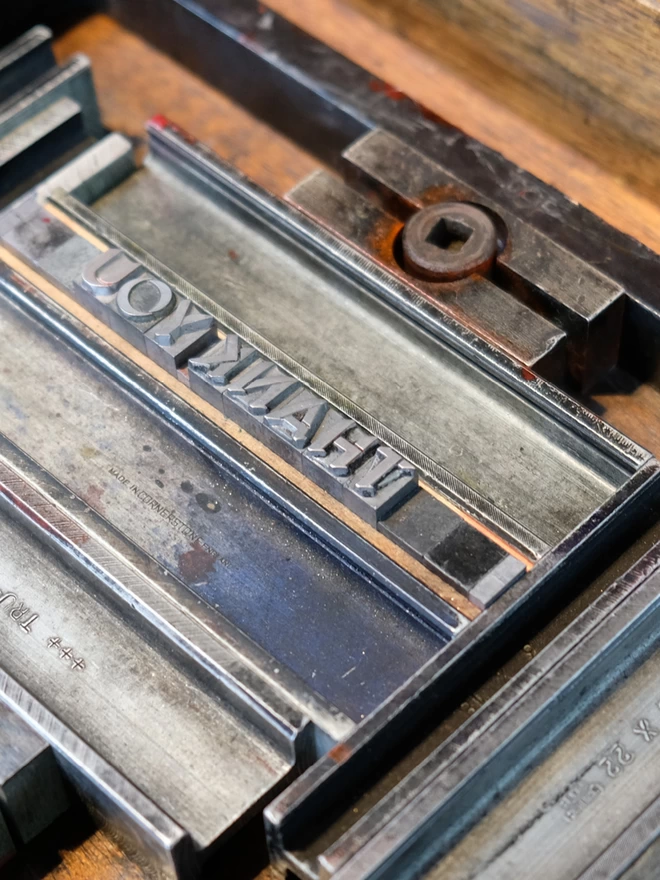 Metal type set in a chase spelling the word 'Thank you' backwards.