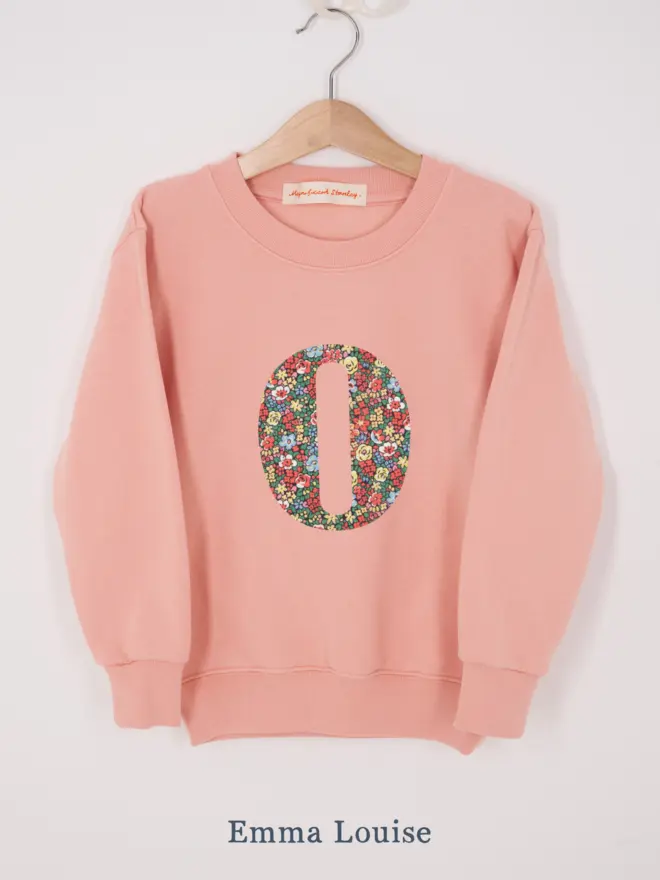 a personalised dusty pink sweatshirt with her initial sewn on the front in floral  liberty print 