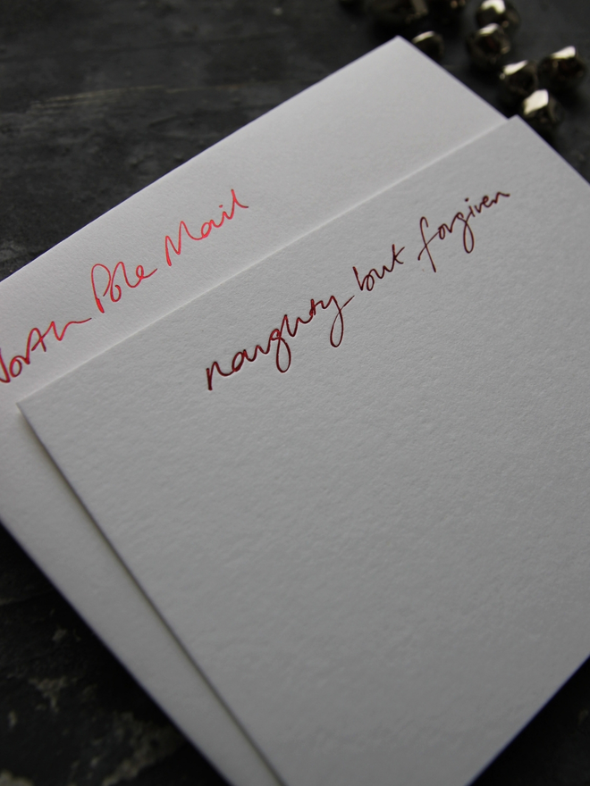 Christmas notecard from Santa that has a tick box for Naughty But Forgiven in red foil with an envelope that says North Pole Mail