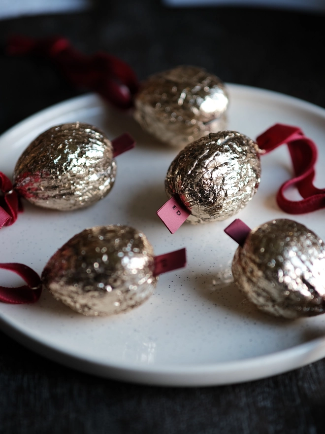 Handmade walnut Christmas ornament with delicate gold gilding, showing the natural shape and grain of the wood. A traditional, nostalgic Christmas tree decoration with timeless old-fashioned charm.