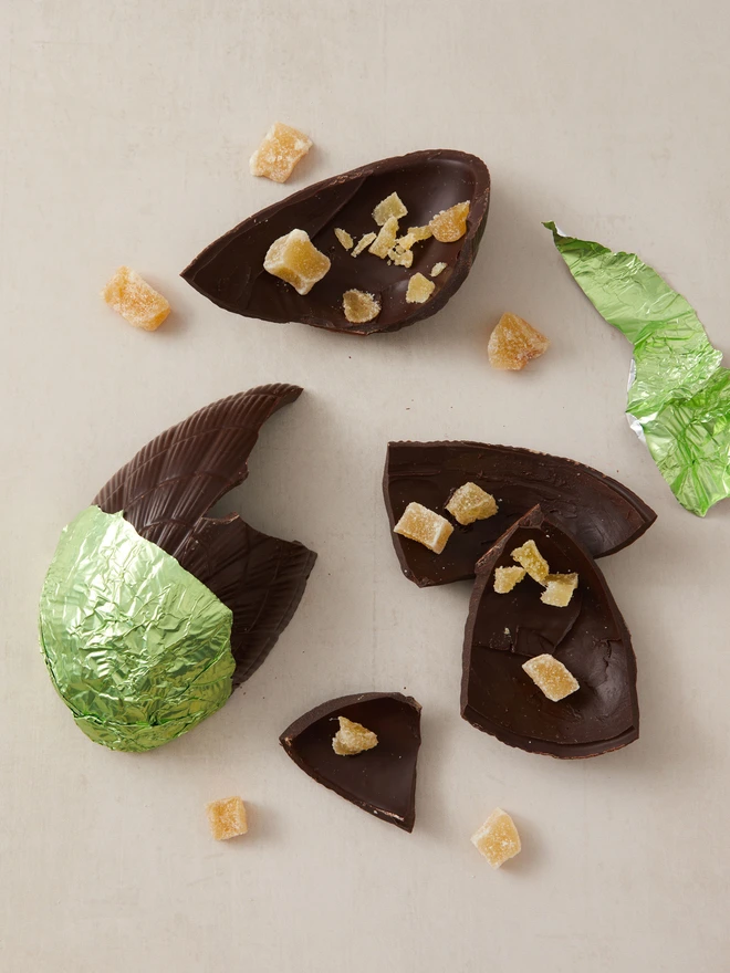 ginger dark chocolate easter egg 72%. a dark chocolate easter egg photographed partly unwrapped from green foil with crystallised ginger.