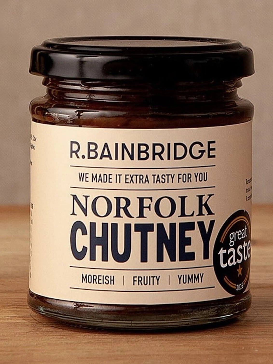 The Great Taste Hamper, a jar of chutney sitting on a wooden surface in front of a plain backdrop. 