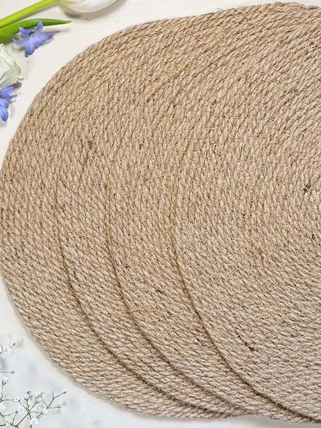 Close up of a round woven seagrass neutral placemats, shown on a light surface. 