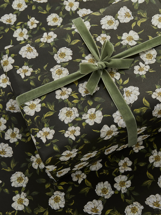 cottage roses floral gift wrap sheet. a box wrapped in black illustrated floral gift wrap with a purple ribbon.