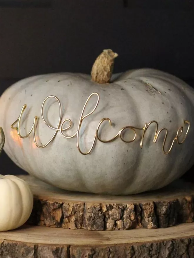 Welcome gold wire sign seen in a green pumpkin.