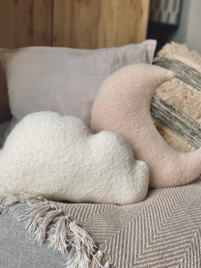 boucle moon and cloud pillow set. a beige moon and white cloud cushion on a sofa.