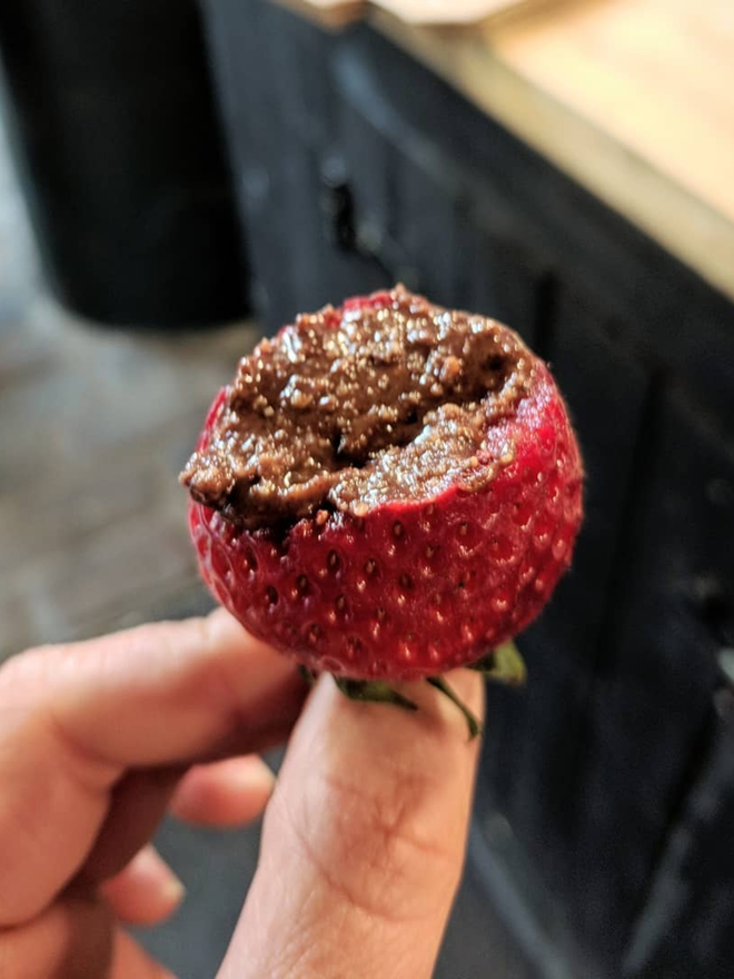 cacao and hazelnut butter. a half-eaten strawberry smothered in chocolate hazelnut spread.