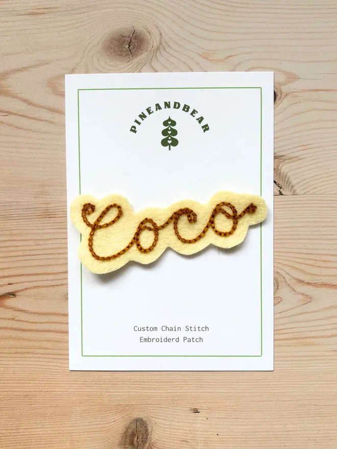 Personalised Chain Stitch name patch in cream and bronze on a white presentation card