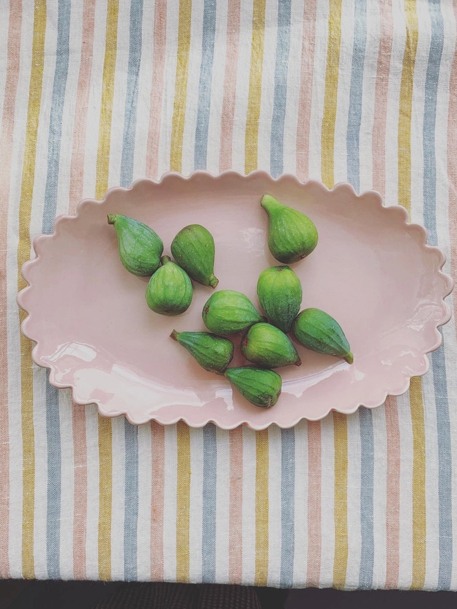 blossom pink oval serving bowl on a striped fabric with figs in bowl