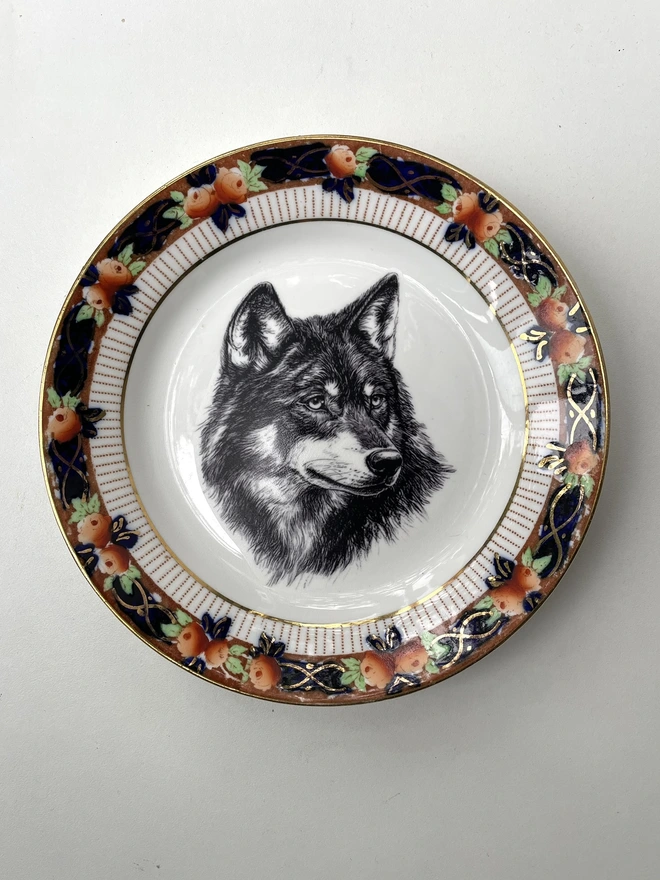 a vintage plate with an ornate border, in the centre of the plate is a vintage style black and white illustration of a beautiful wolf