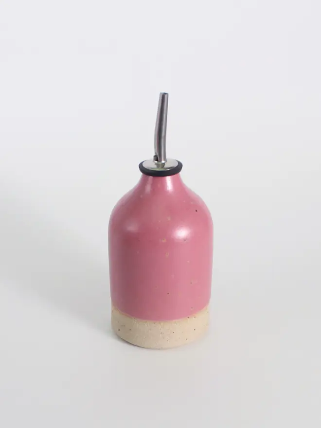 Small ceramic oil pourer in fuchsia against a white background