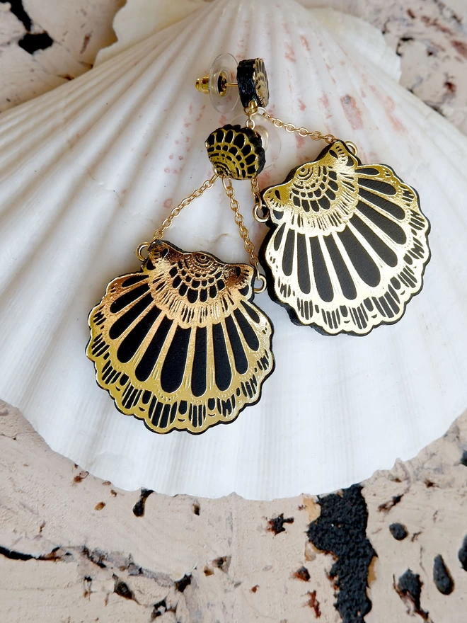 black & gold leather clamshell earrings on shell