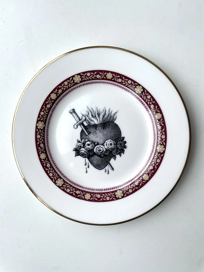a vintage plate with an ornate border and in the centre is an old illustration of a beautiful sacred heart