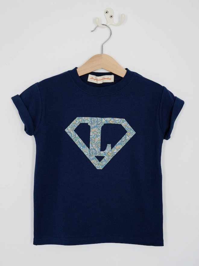 a personalised kids navy t-shirt with a superhero initial cut from liberty dragon print on the front