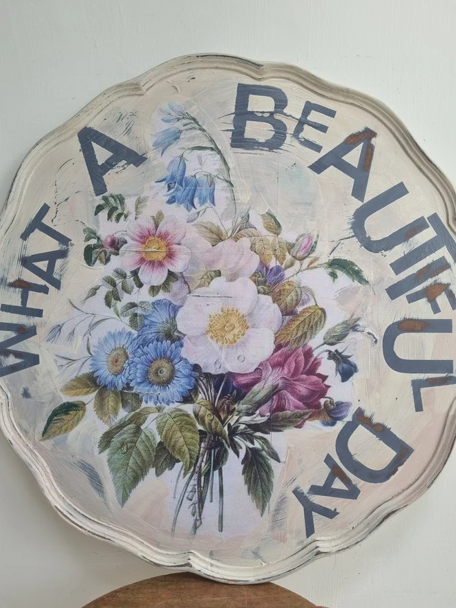 Art Panel made from a 'pie crust' table top. A pale background with mauve flowers and writing in mauve that says 'what a beautiful day'.